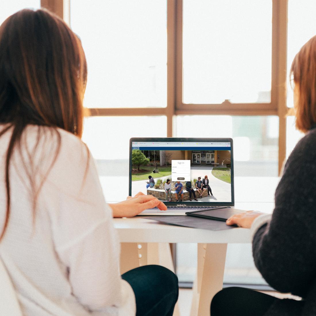 two female students logging into to school laptop