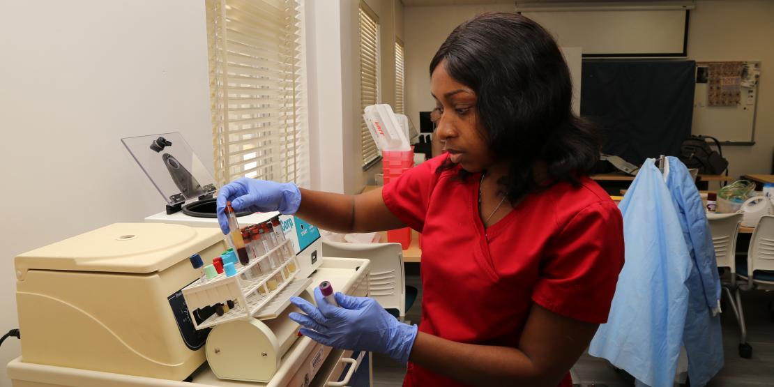 Phlebotomy student examines vials of blood