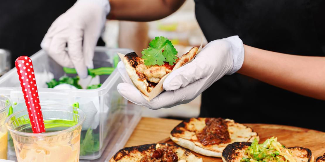 Food service worker prepares taco and tops with cilantro