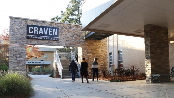 Students walking outside under exterior sign