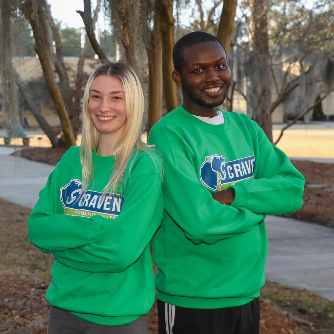 Female and male Craven CC ambassadors with arms crossed, leaning back to back outside