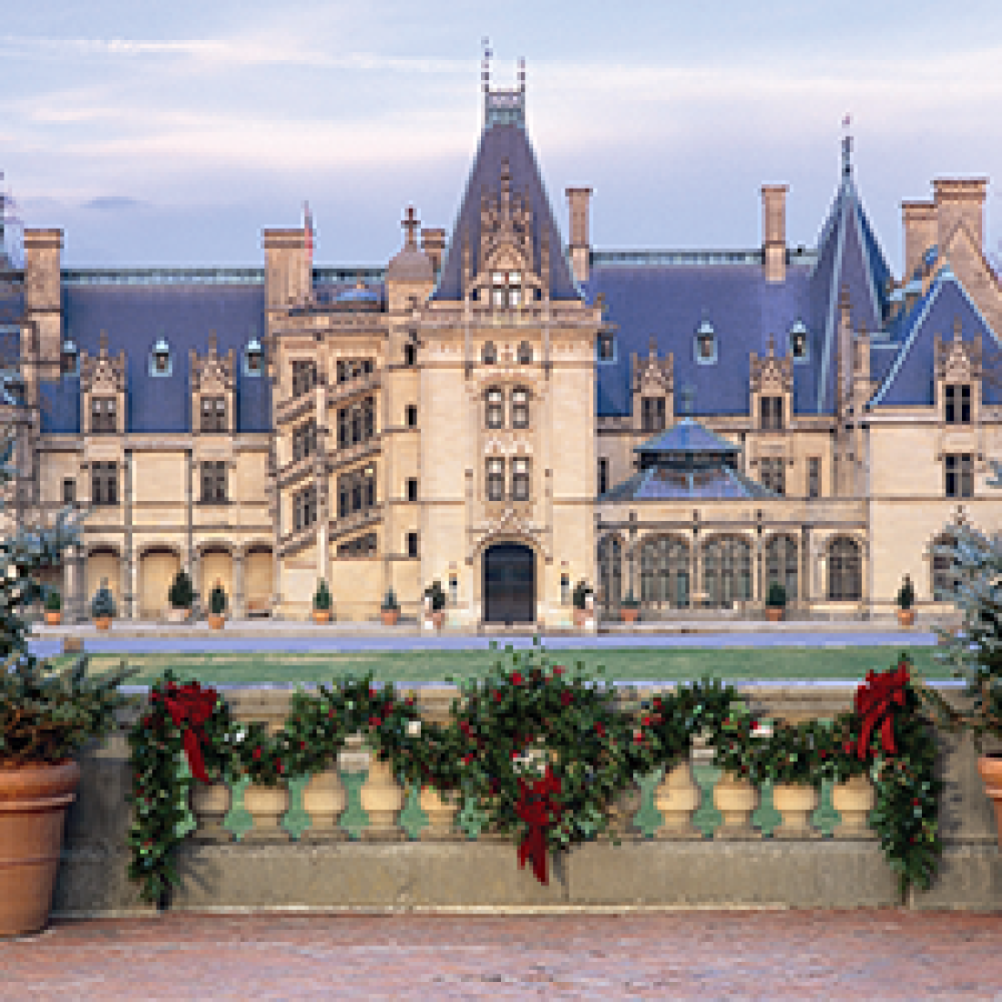 Biltmore Estate with front gate decorated with garland, red bows, and a wreath